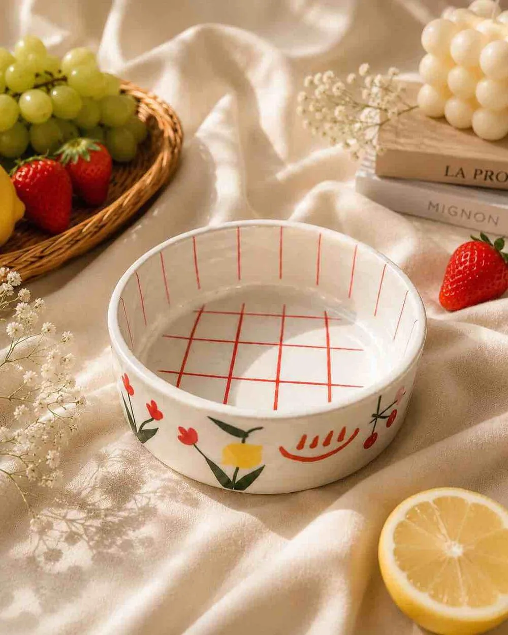 A white bowl with a red grid inside and tulips painted round the outside