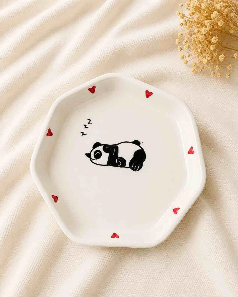 A plate with a small sleeping panda painted in its centre